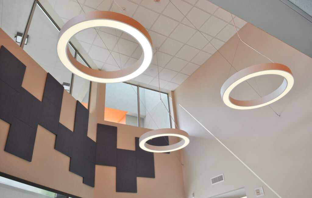 Modern circular lighting design inside Mabel Mattos Elementary School’s administration building, enhancing the bright and open interior.