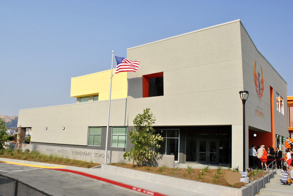 Front view of the Mabel Mattos Elementary School building with the American flag and colorful design elements.