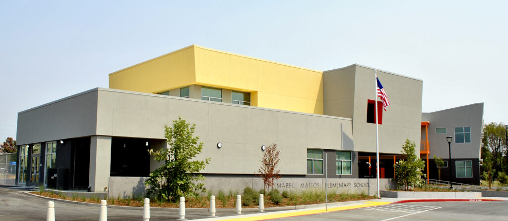 Modern architecture of the main building at Mabel Mattos Elementary School, with yellow and gray design elements.