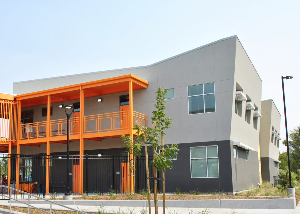 Side view of the classroom building at Mabel Mattos Elementary School, with orange accents and exterior walkways.