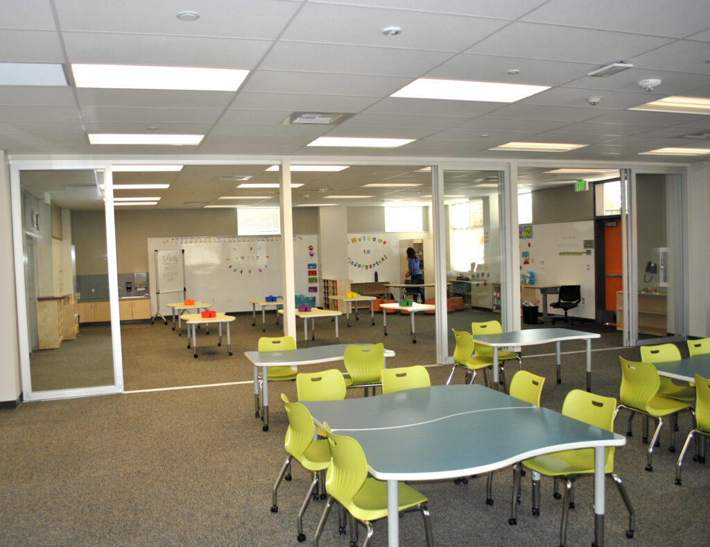 Interior of a flexible learning space at Mabel Mattos Elementary School featuring modern tables and breakout areas.