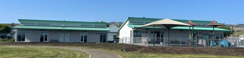 Exterior view of the new modular classrooms at Old Adobe School, featuring a playground and covered outdoor areas.