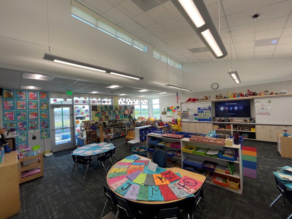 Bright and spacious interior of a kindergarten classroom at Old Adobe School, featuring colorful workstations and ample natural light.