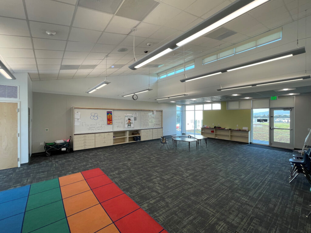 Spacious and well-lit interior of the TK classroom at Old Adobe School, featuring a colorful rug and built-in storage.